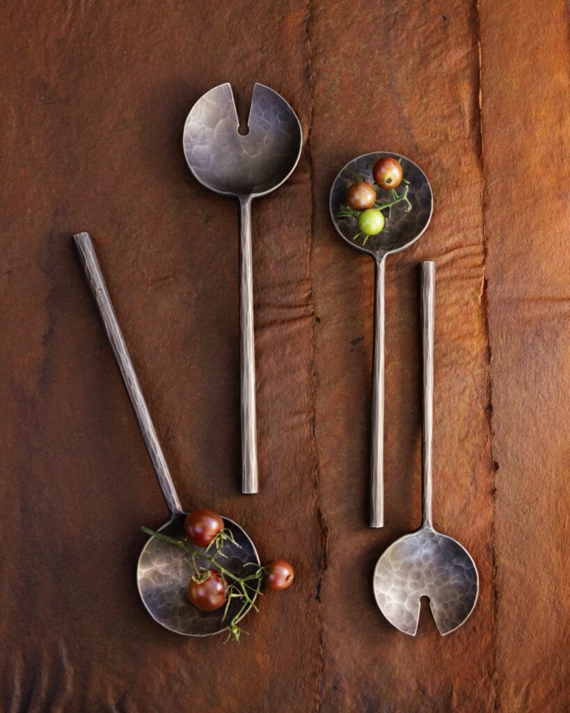 Four spoons with a clice out of the middle sit on a brown background. The first and third spoon hold little berries inside them.