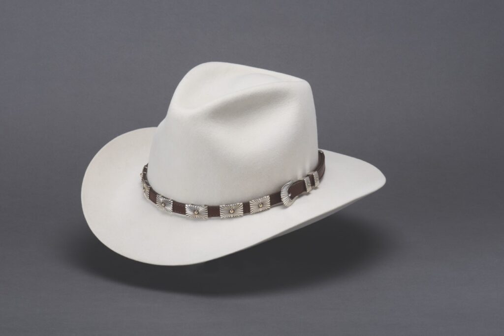 A white cowboy looking hat for men with a silver band around the hat.