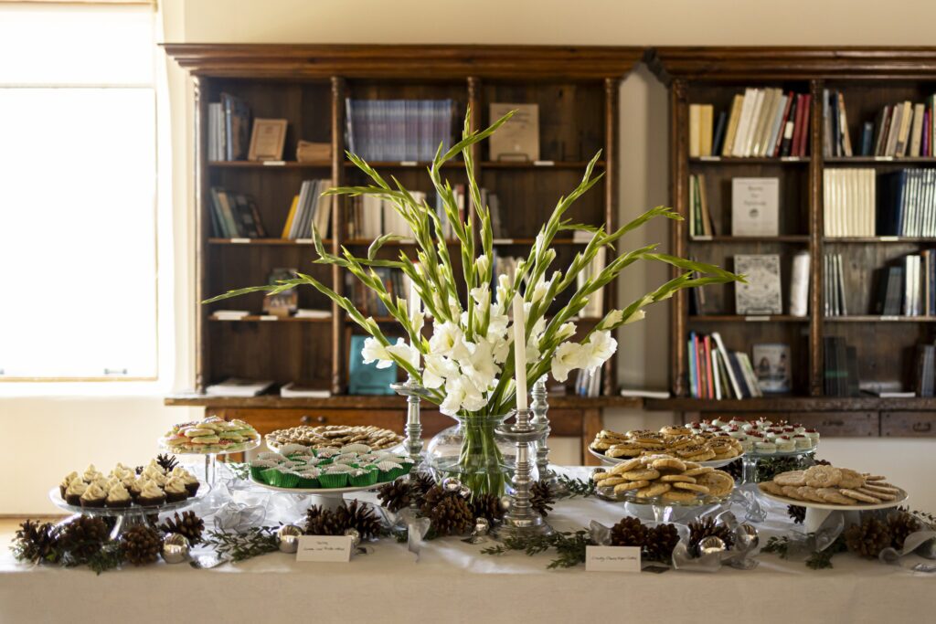 A table full of holiday cookies sits decorated in front of a bookshelf.