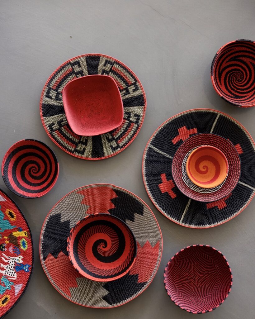 7 red spiral patterned wire wrapped baskets sit on a grey background, scattered about.