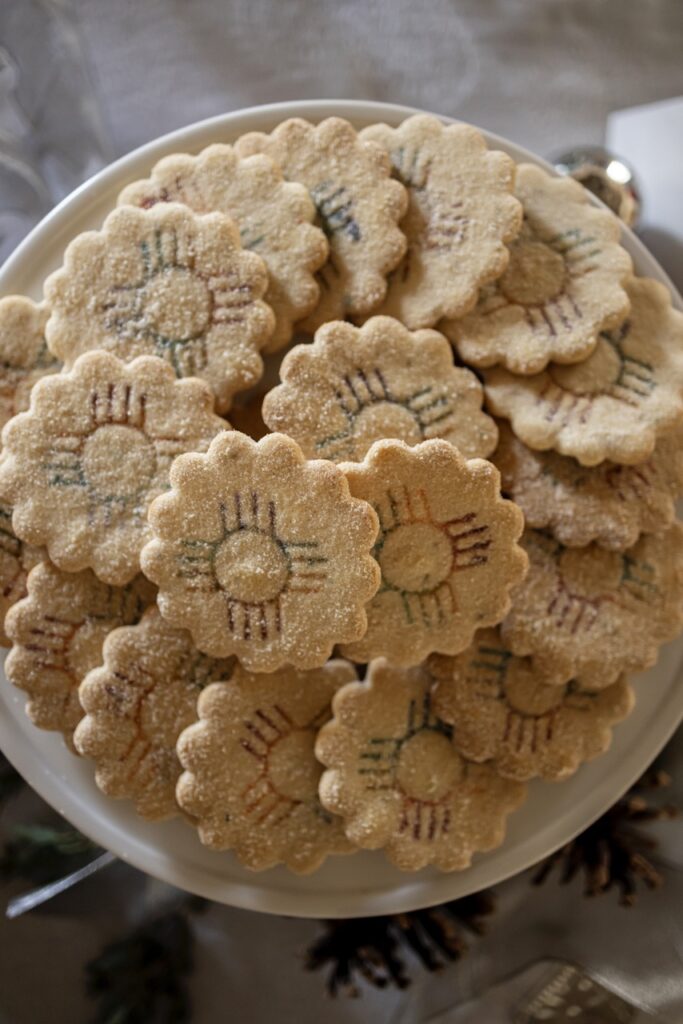 A pile of flower-shaped biscochitos are arranged in a circular shape. 