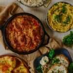 A skillet of Chicken Chaap beside slices of bread from Asma.