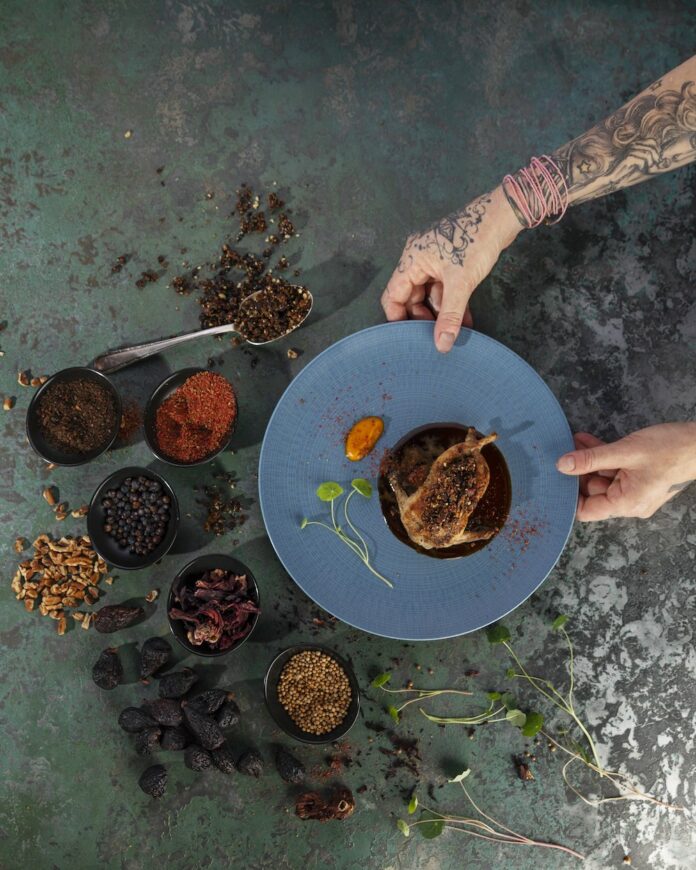 An aerial view of a blue plate with grilled quail with balsamic reduction.
