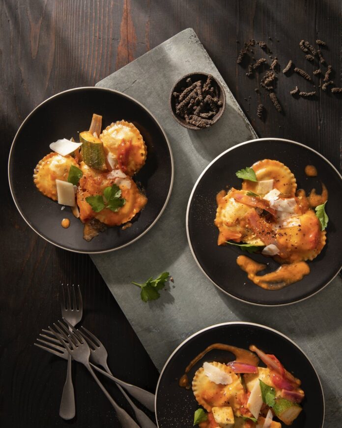 Three plates of ravioli on a black background