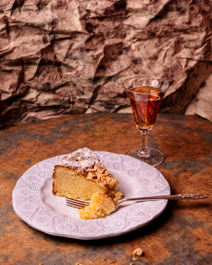 Mille Santa Fe cake on a white plate next to a glass with a brown beverage