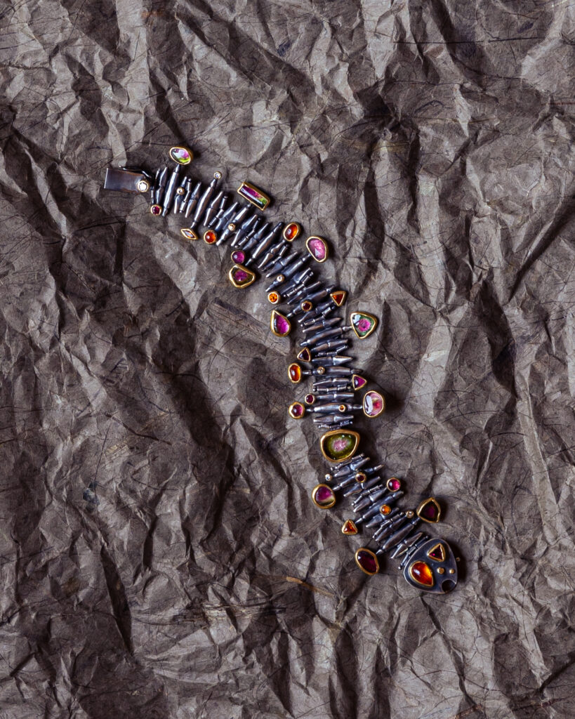 a bracelet that looks like an inchworm, pink and orange jewels are where the legs would be