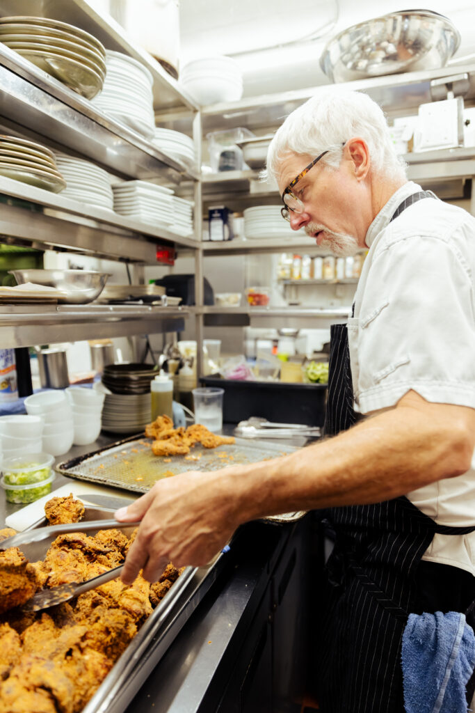 Chef David prepares the fried chicken at a kitchen station for the staff meal.