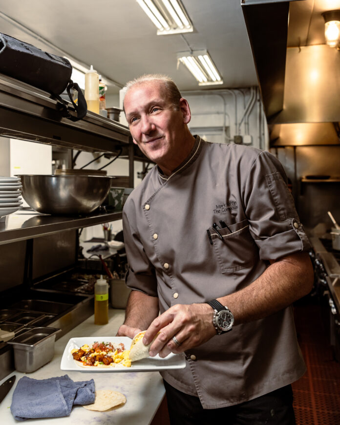 Owner Mark Kiffin pictured in the kitchen with a plate of tacos.