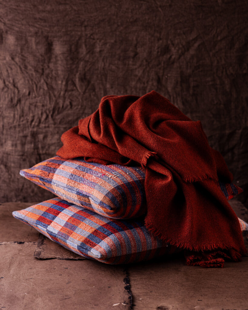 Two plaid pillows with a red throw on top.