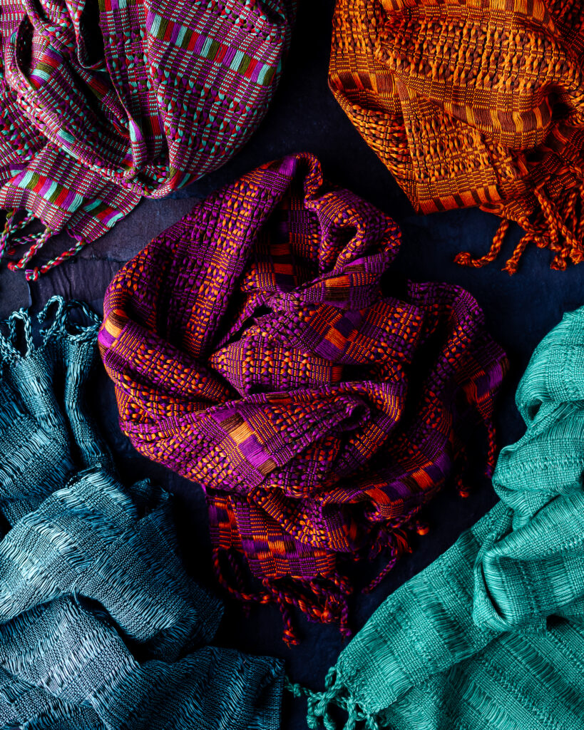 A bunch of scarves swirled together, colors in red, orange, blue, and green