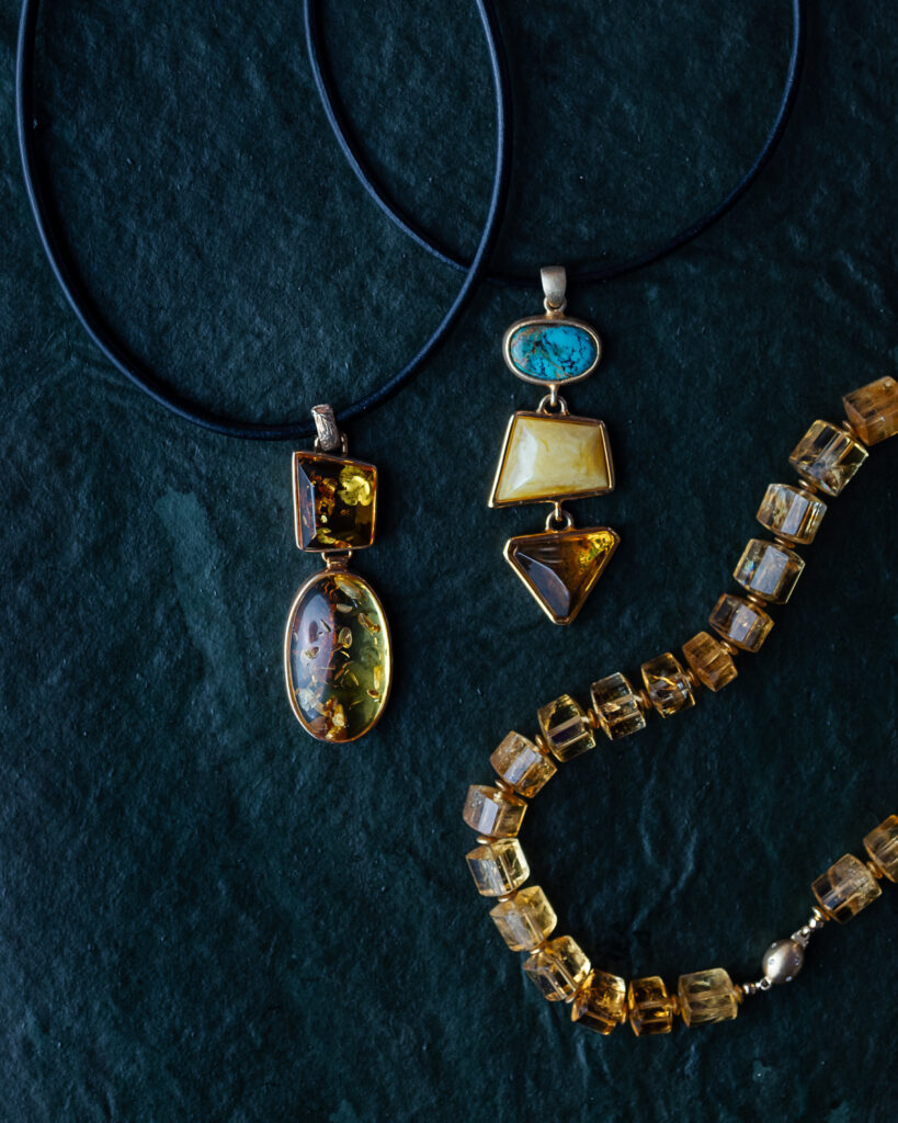 Three necklaces made from amber. Two pendants on black strings, one with all amber gems. jewelry gifts for women
