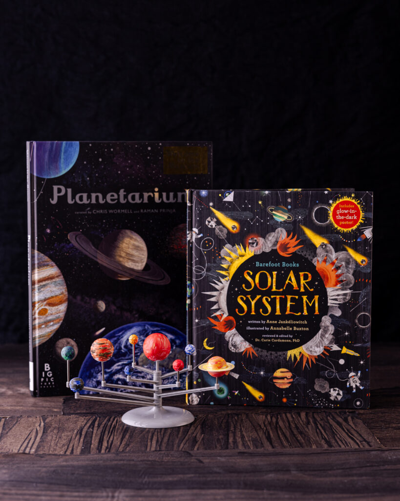 Two books face outwards, both with black covers, one says planetarium, the other says solar system. Gift Ideas for Kids