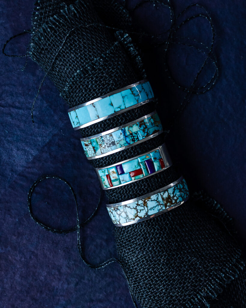 a chunky silver bracelet, inlaid with turquoise and other stones