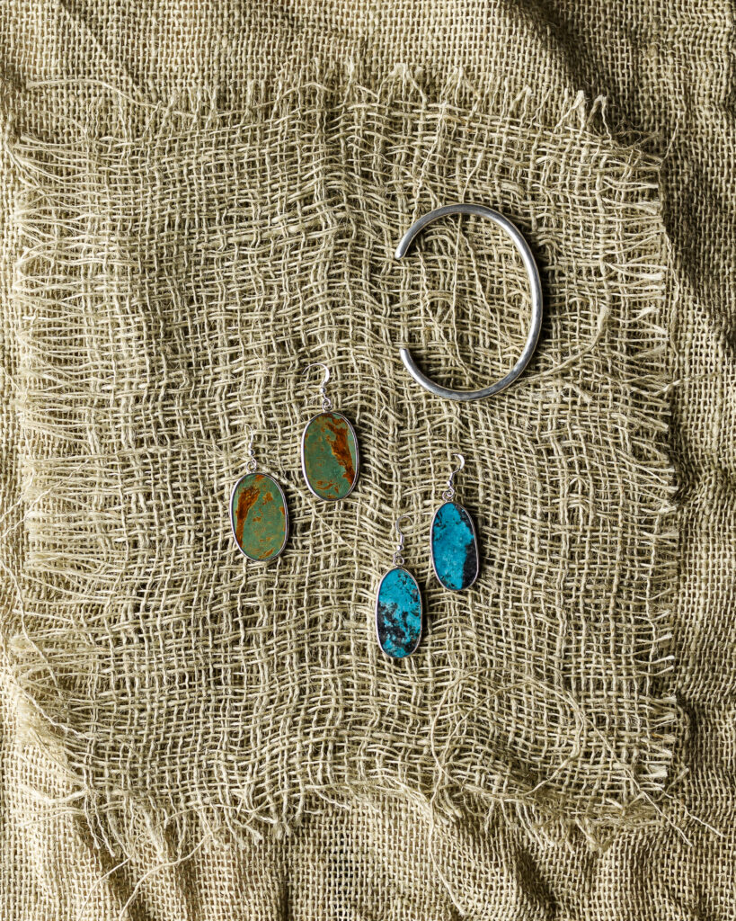 Two pairs of handmade earrings, one green, one blue, and a silver cuff bracelet