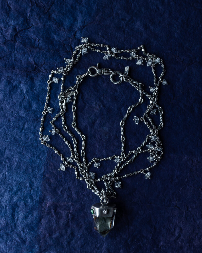 A silver necklace with multiple chains against a blue velvet background