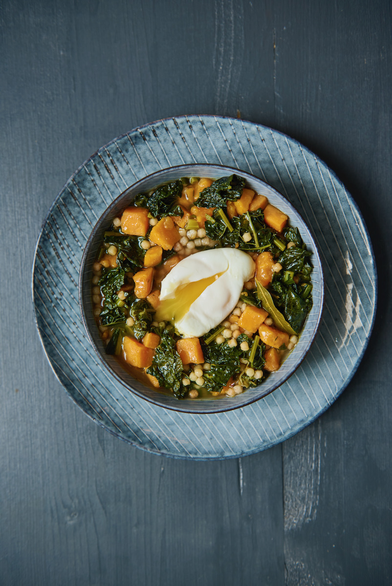 A plate of kale and sweet potato soup with a poached egg