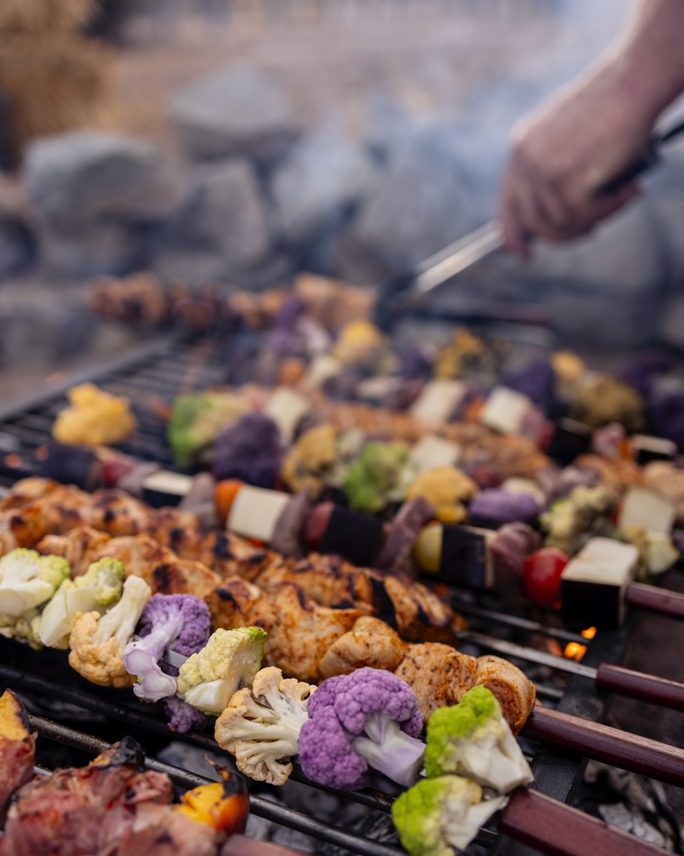 A hand grills various colored vegetable skewers for the Double DD Ranch Dinner Party. 