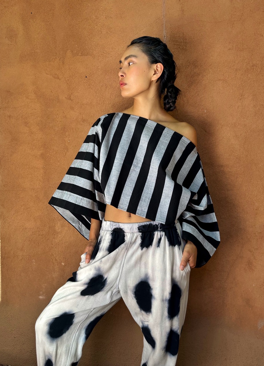 A woman poses in a black and white striped crop top with matching tie-dye pants.