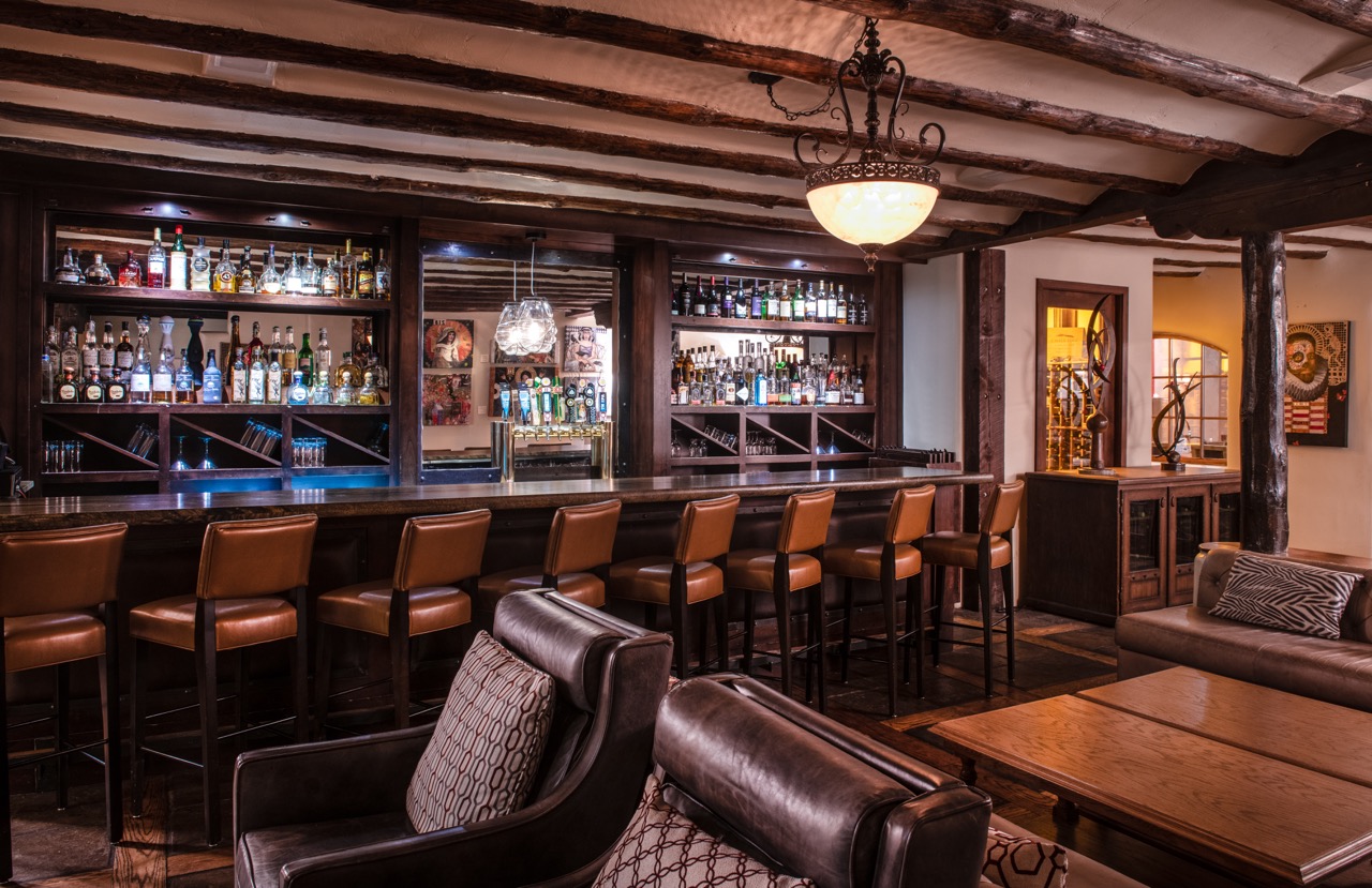 The bar at La Posada is lined with leather chairs and low lighting as shelves of liquor sit in the background.