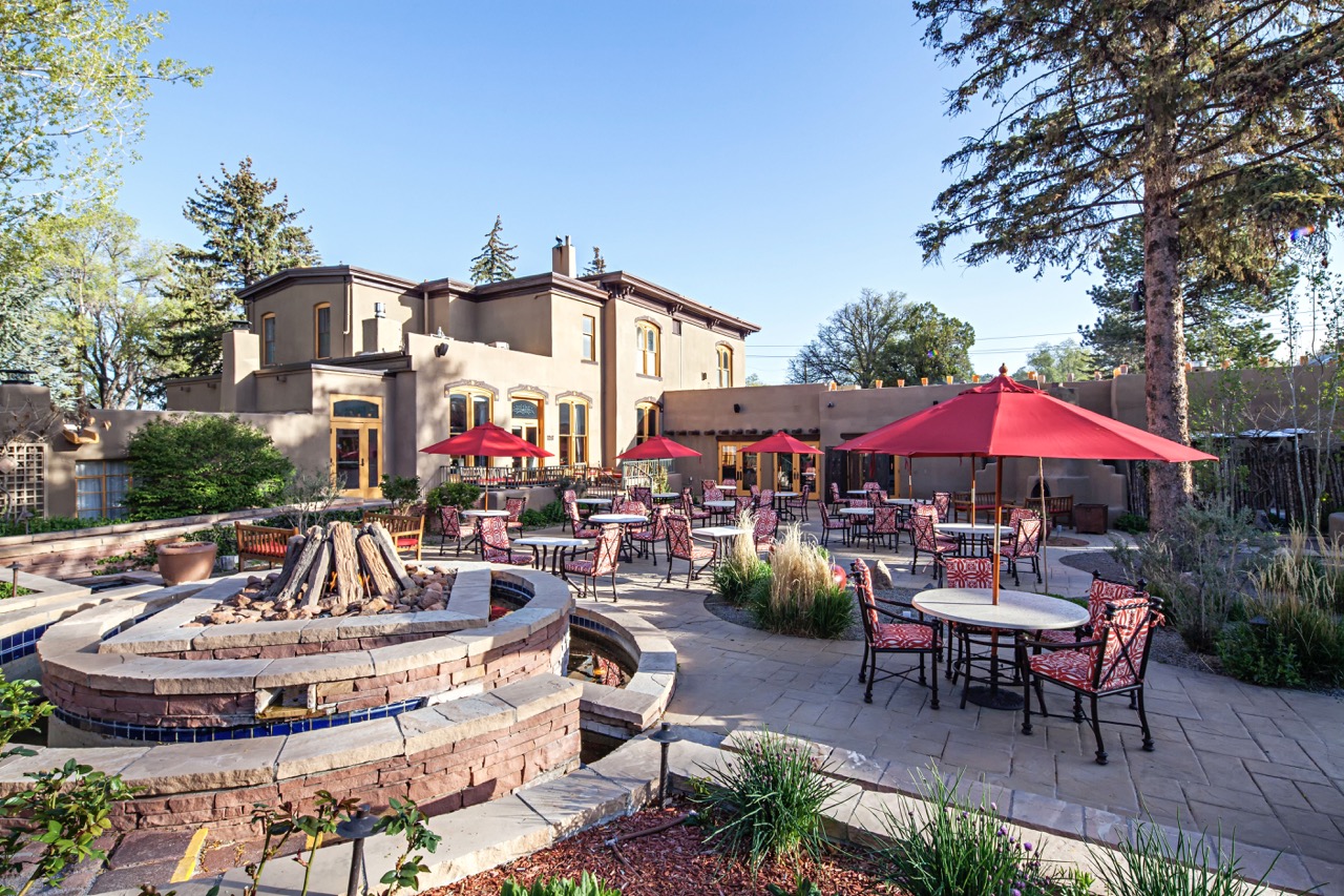 The outside deck at La Posada featuring many umbrella covered tables and a big fire pit.