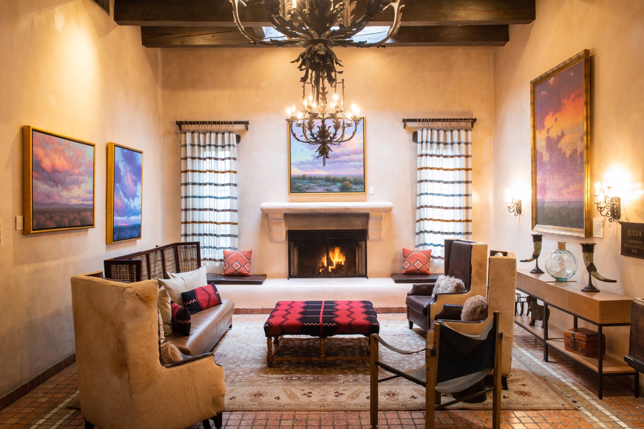 An interior of a lounge with couches and tables and a fireplace in the background.