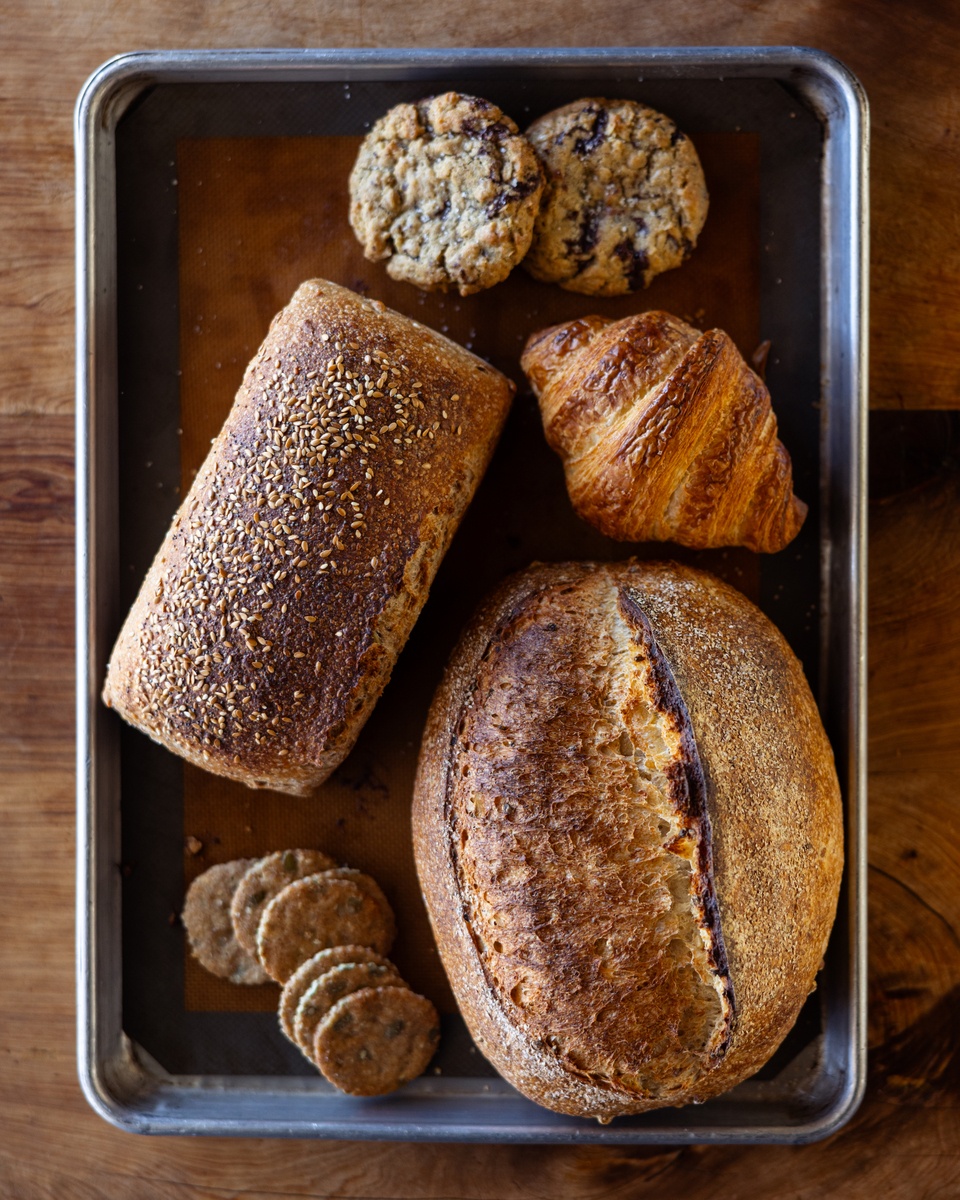 A variety of baked goods, including bagels and muffins, are displayed in a baking tray.