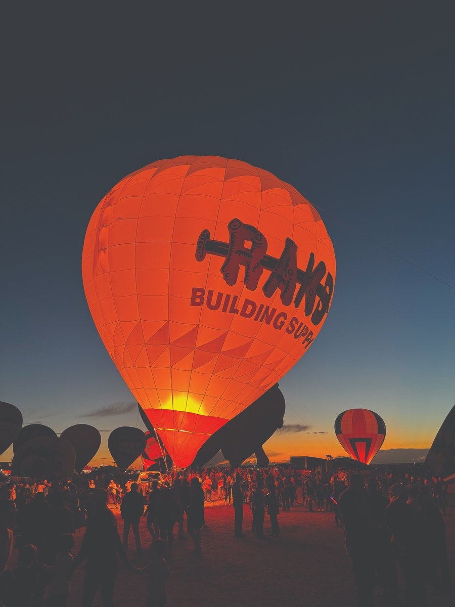 Illuminated hot air balloon at sunset with 'BUILDING SUPPLIES' branding