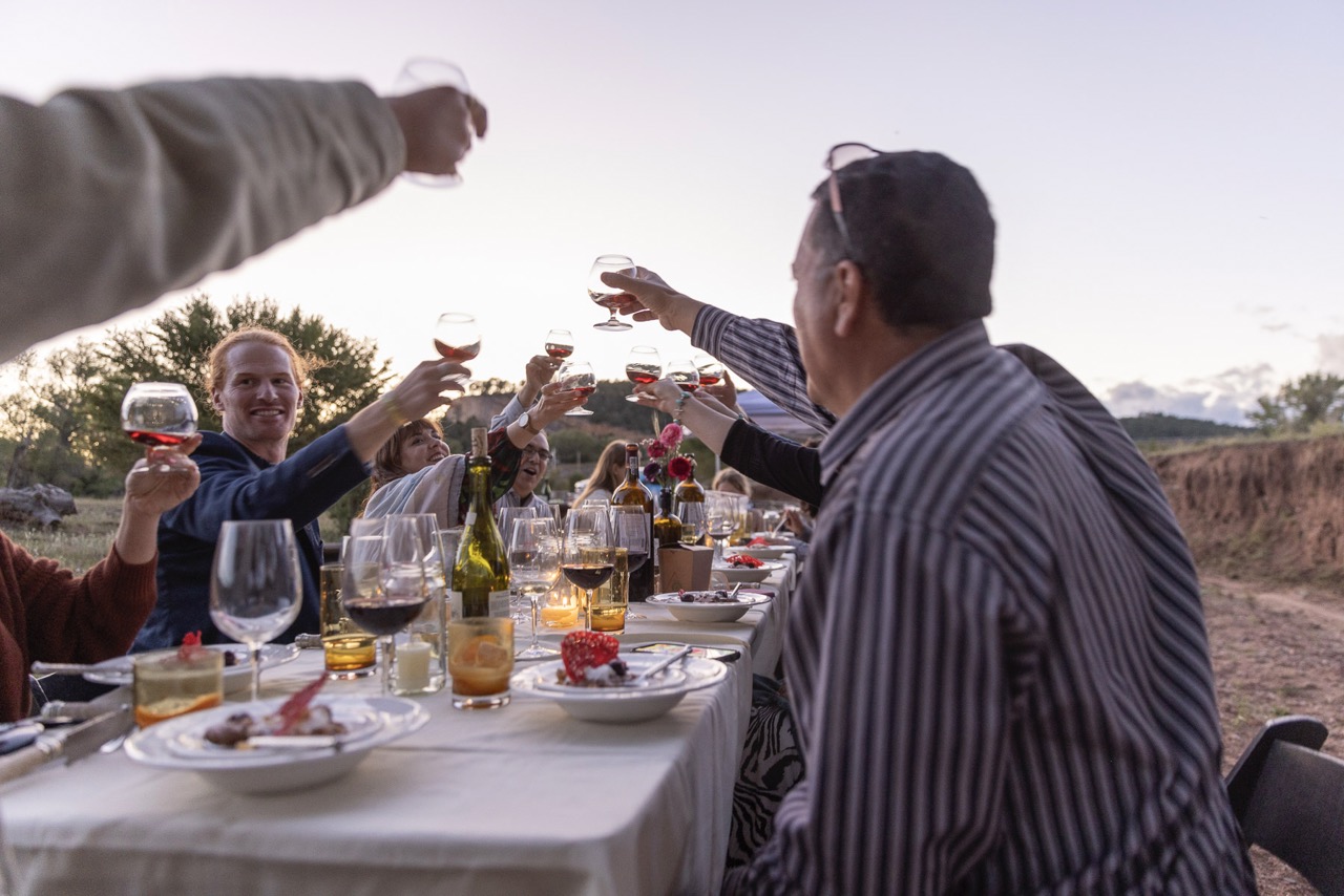 A group of dinners raise their glasses over a white dining table. 