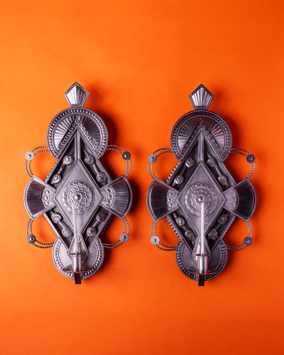 Decorative silver wall hangings on an orange background, showcasing intricate designs and craftsmanship.