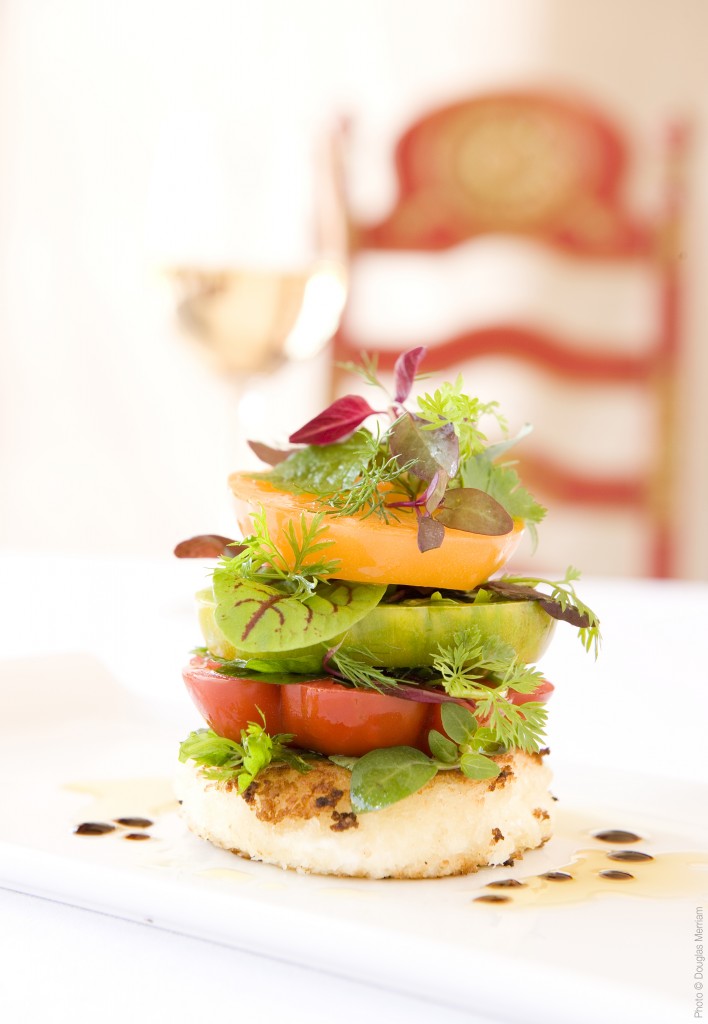 Red heirloom tomato resting on a wooden cutting board, showcasing its naturally rugged exterior and deep coloration.