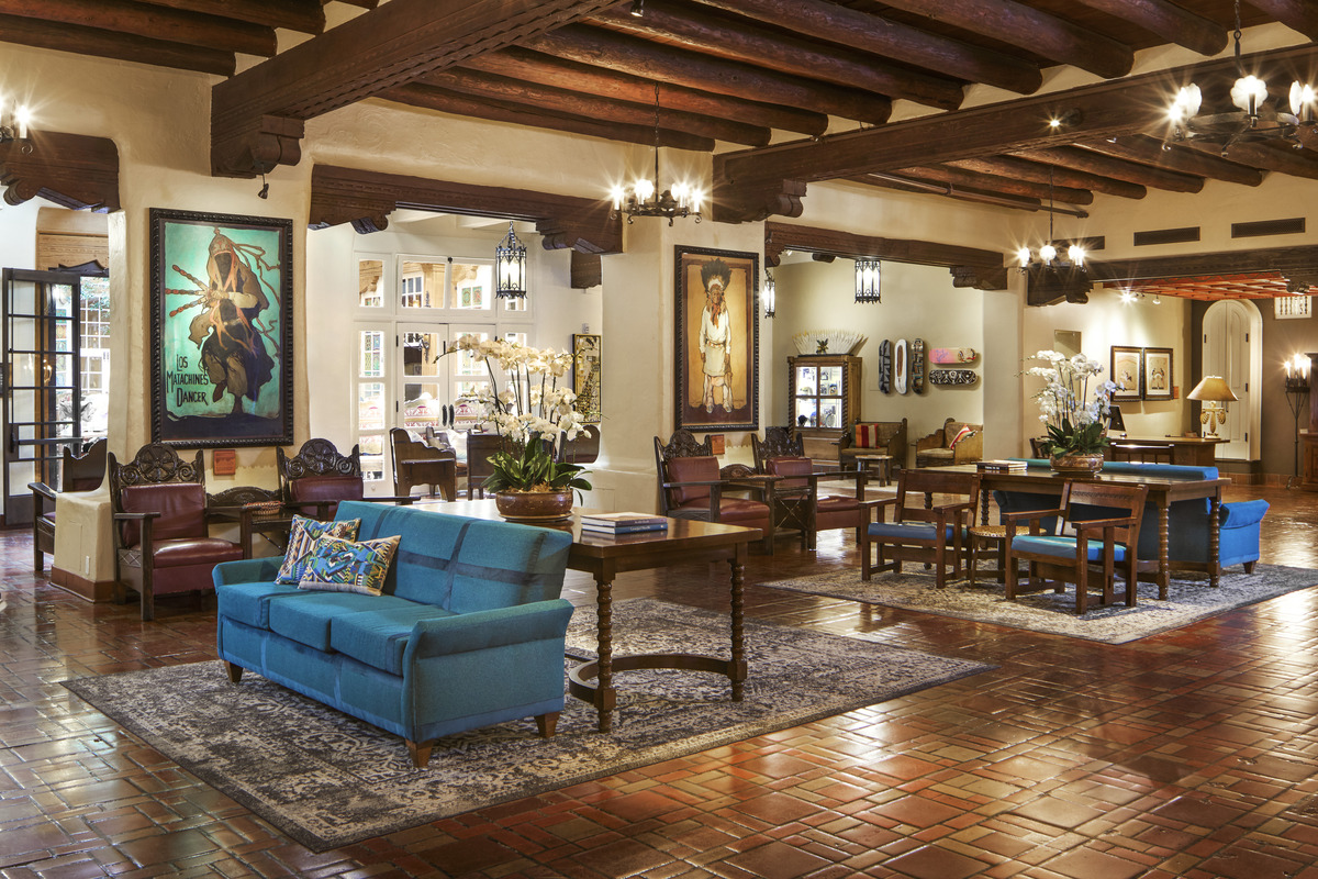 Stylish hotel living room featuring varied comfortable seating arranged around a wooded coffee table, adorned with art and decorative accents in a blend of traditional and modern aesthetics.