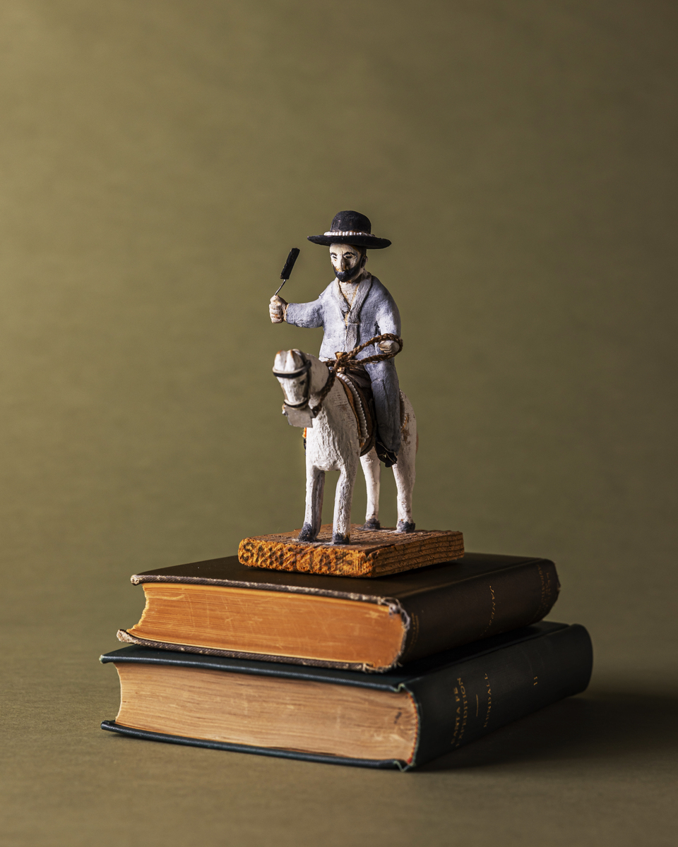 Figurine of a man on a horse atop vintage books, representing history and culture.