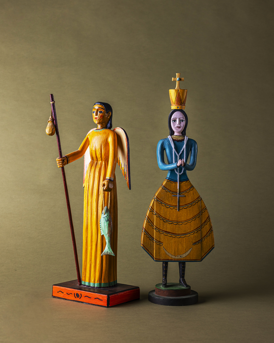 Colorful wooden figurines depicting a female angel and a queen, showcasing traditional craftsmanship against a muted background.