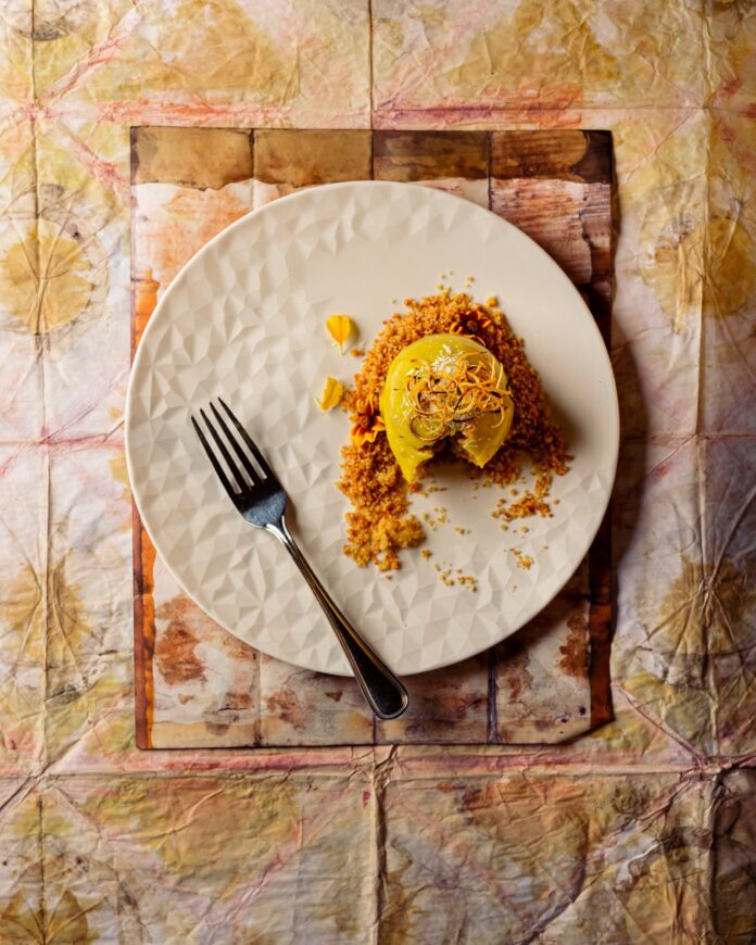 On a white plate sits a yellow recipe from Nob Hill restaurant, Scalo. A fork sits nearby on the plate and it's all against a brown background.