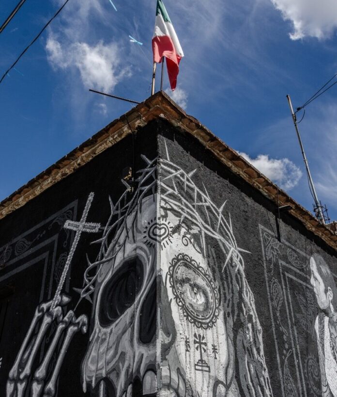 A sugar skull painting sits on the corner of a building.