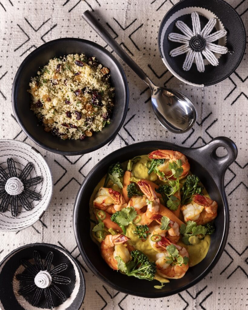 Two larger dishes sit on a white table cloth with quinoa in the one and shrimp and veggies in the other.