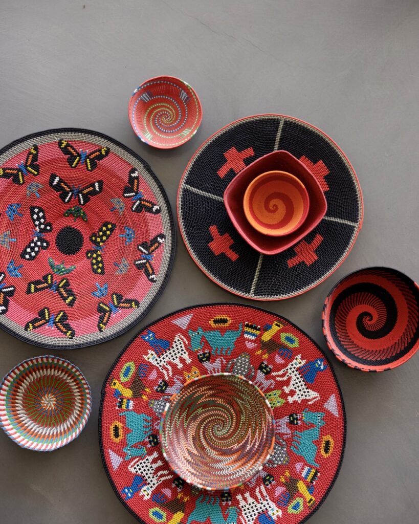 A variety of red wire wrapped basket tops sit on a grey table in various patterns such has cats and butterfies.