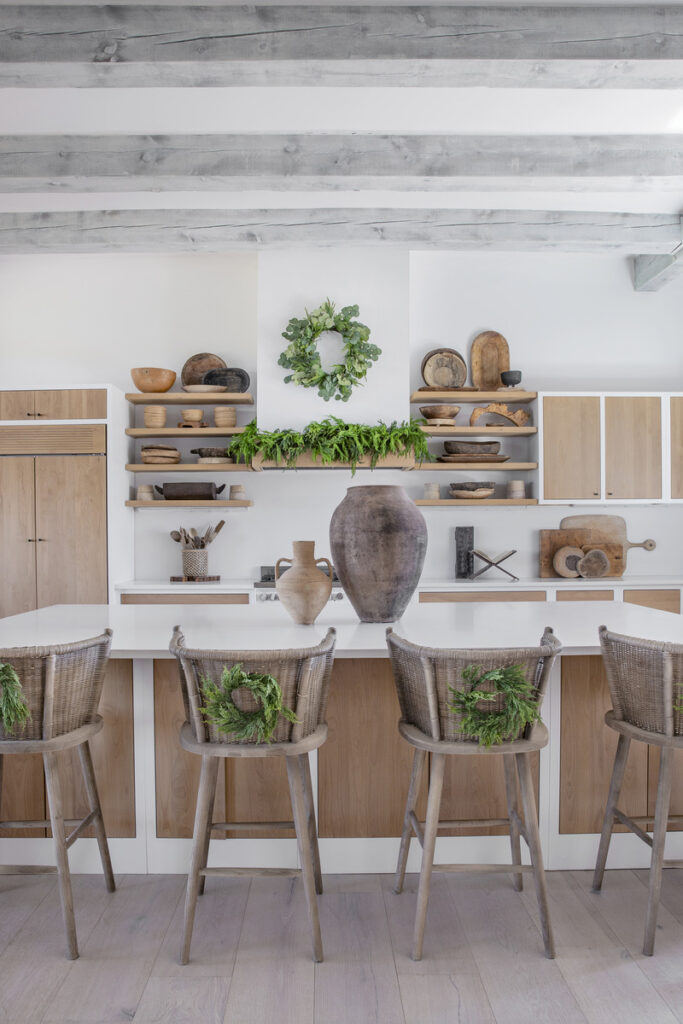 A warm kitchen adorned with wooden shelves and chairs, showcasing a harmonious mix of travel artifacts and seasonal decorations.