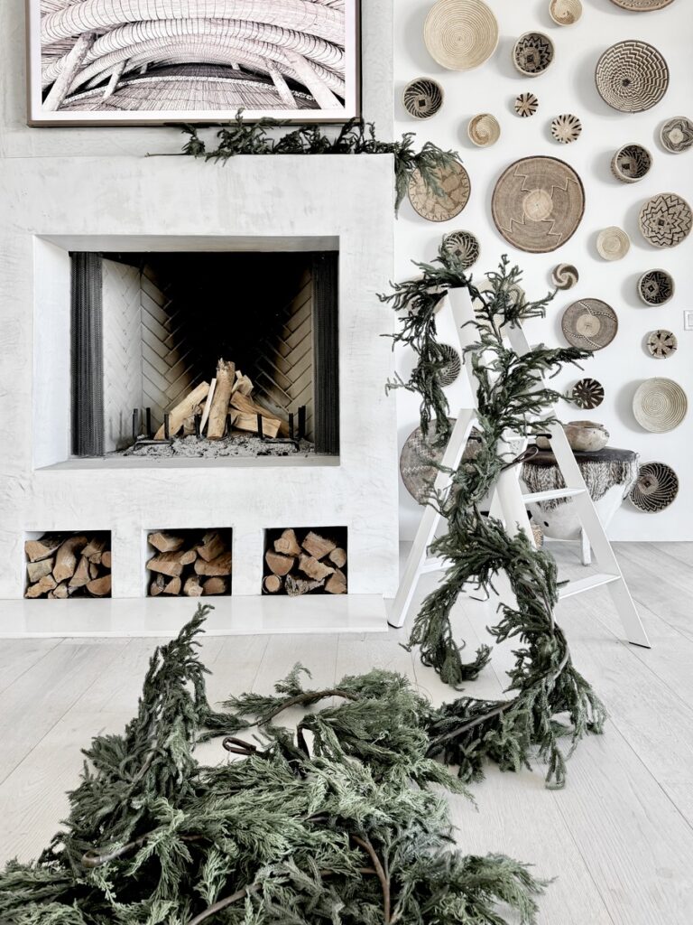 A charming fireplace with a Christmas tree and wreaths on the wall, enhancing the festive spirit in a tastefully designed living space.