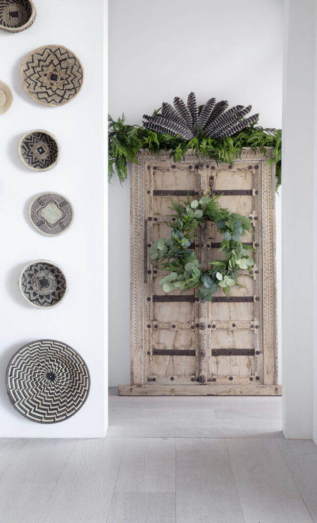 An inviting space with a wooden door and a wall adorned with intricately arranged baskets, showcasing global artistry.