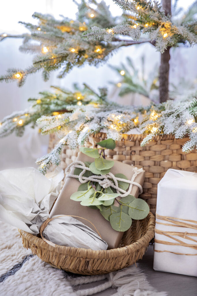 A beautifully arranged basket filled with gifts sits beside a decorated Christmas tree, embodying the festive spirit of the season.