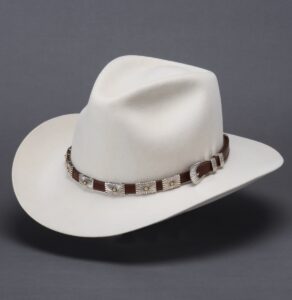 A white cowboy hat with a black band on it sits on a grey background.