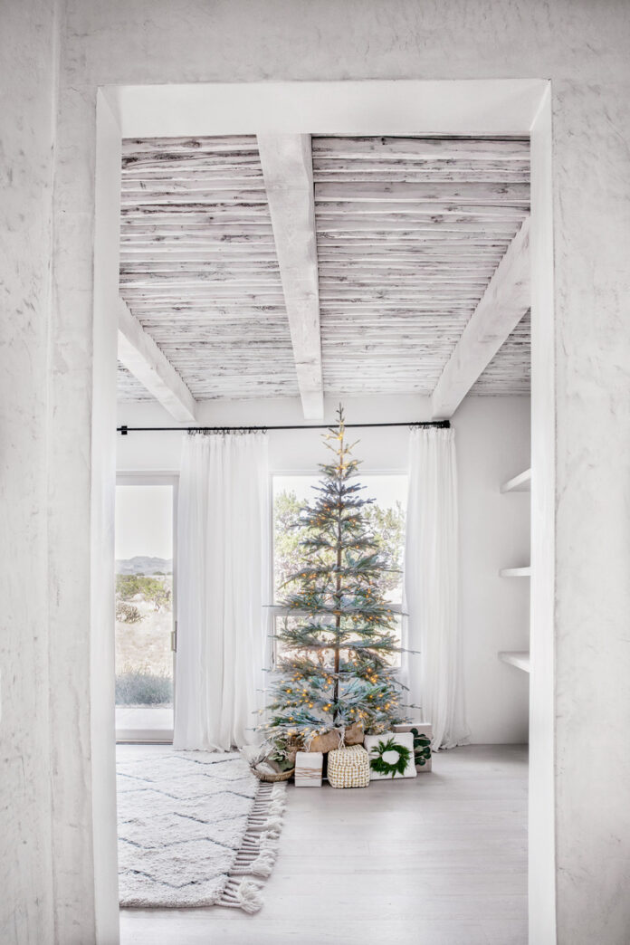 A bright white room featuring a decorated Christmas tree and a cozy rug, capturing the festive spirit of New Mexico.