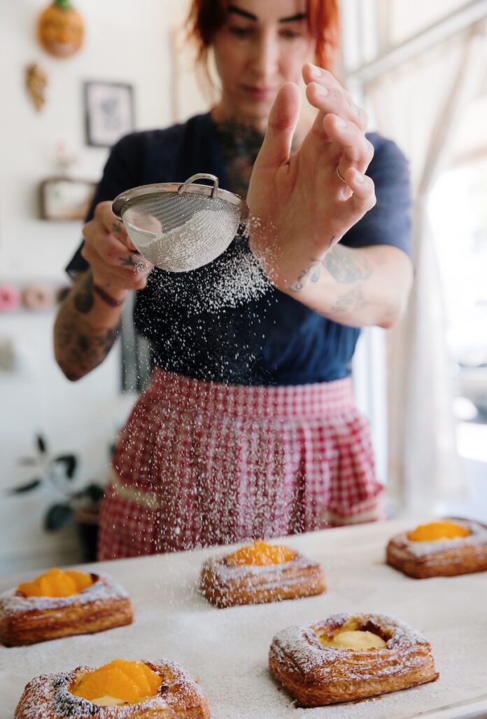 A baker in a red and white apron covered in flour