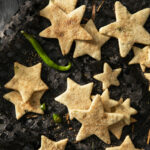 Green chile biscochitos cut into star shapes with green chiles decorating the plate. Biscochitos recipe