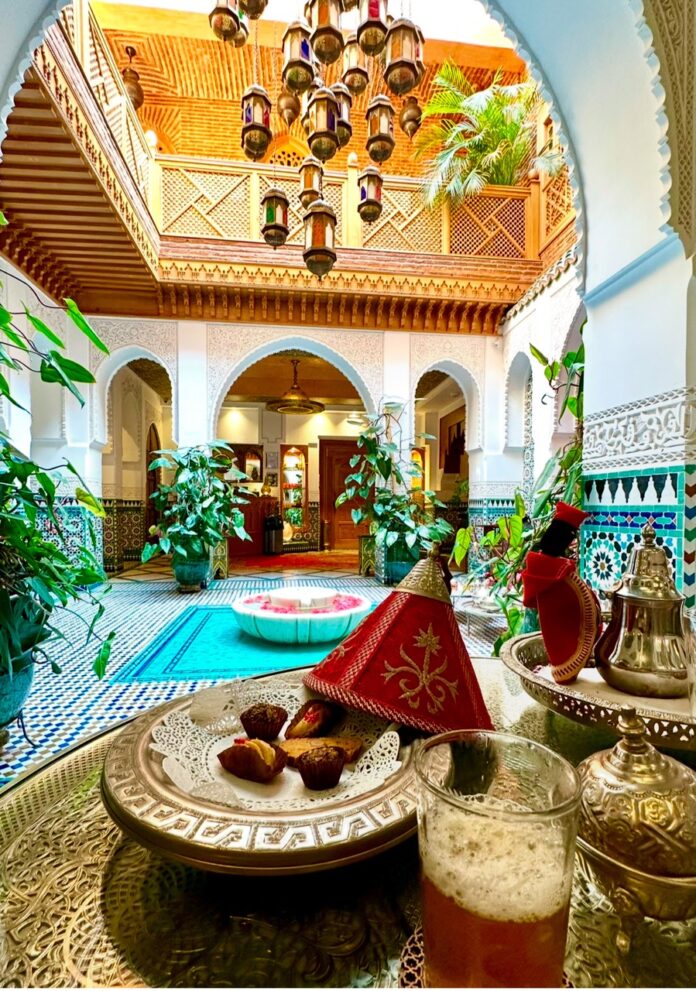 A cocktail from Morocco sits on a table in a beautiful, sunlit outside plaza.