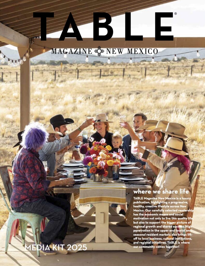 A group of people sit at a table for the cover of table magazine new mexico.