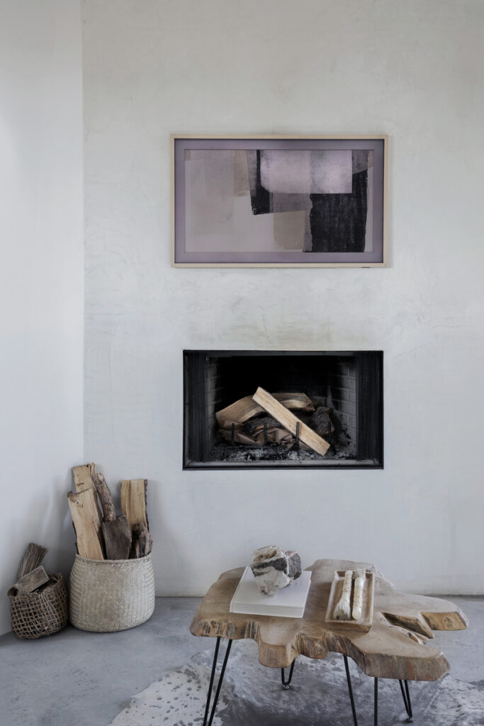 Minimalist living room with a modern fireplace, abstract wall art, and a rustic wooden coffee table.