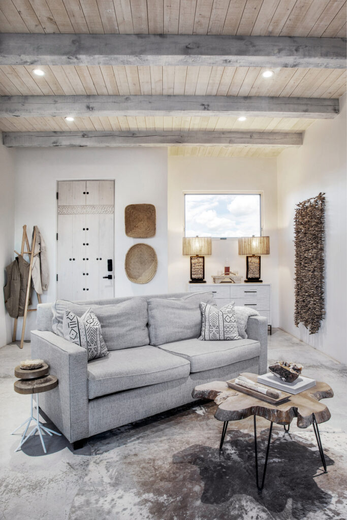 Modern rustic living room with a gray sofa, wooden coffee table, and textured decor elements.