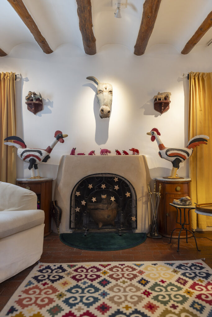 Southwestern adobe-style living room with a rustic fireplace, handcrafted wooden animal sculptures, and traditional decor.